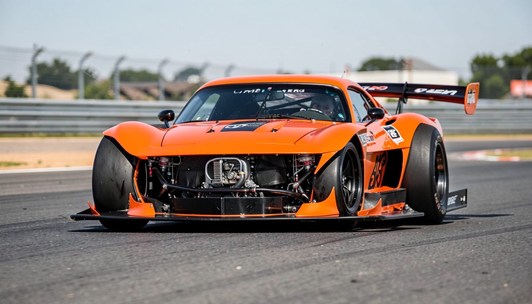 A radical hot rod with F1-inspired aerodynamic bodywork, exposed Honda VTEC engine, and wide racing slicks, shot on a racetrack
