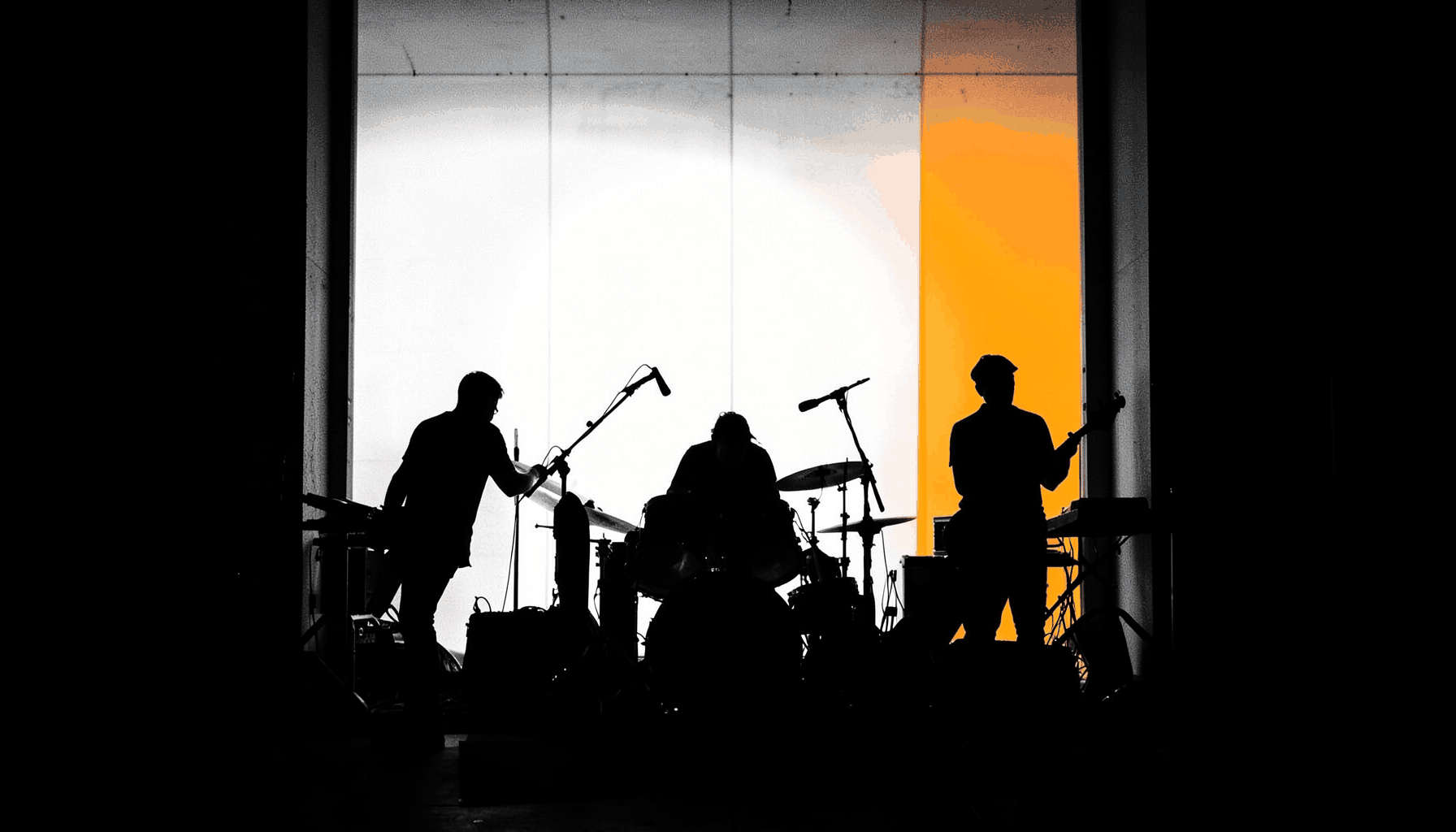 Silhouetted band performing against a wall of light, monochrome with stark contrast, raw rock energy
