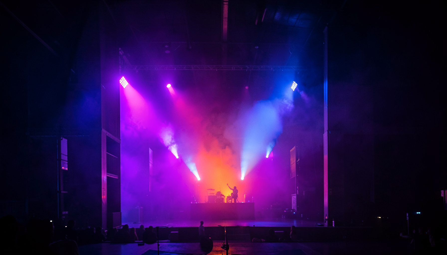 Electric blue and magenta stage lights cutting through haze, rock show energy
